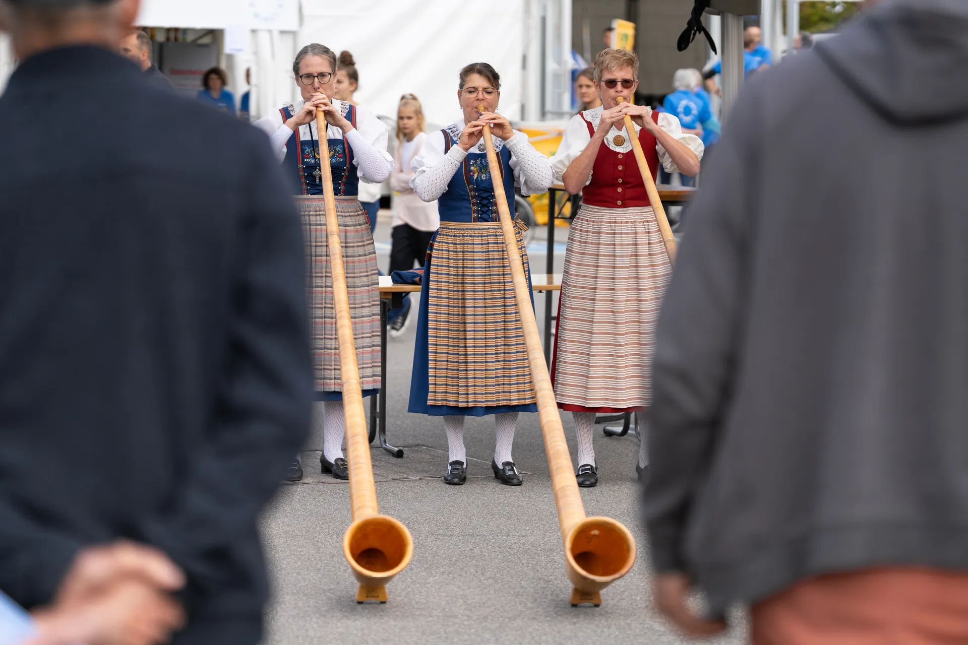 Drei Frauen spielen Alphorn an den Tagen der offenen Tür der Schweizer Paraplegiker-Gruppe.