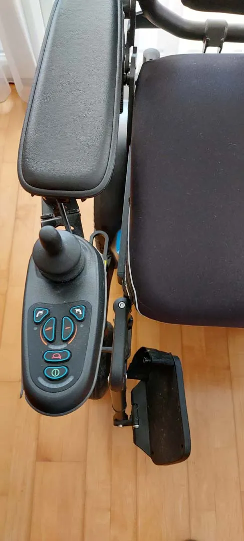 Schwarzer Rollstuhl mit elektrischer Steuereinheit und Joystick an der Armlehne.