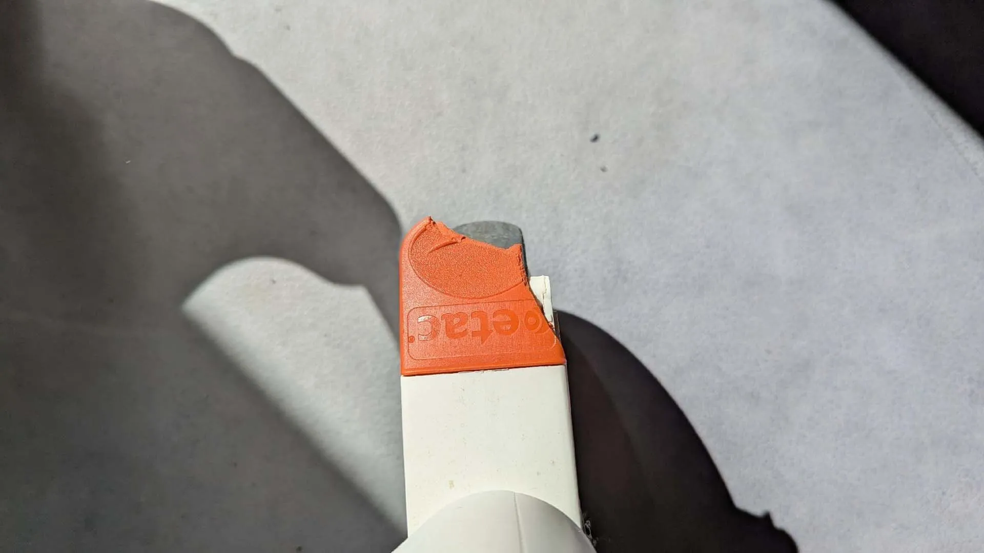 Orange Radiergummi mit weißer Spitze auf grauem Hintergrund.