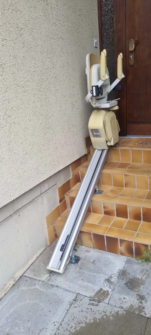 occasion-hoegg-sitzlift-kueffer03.jpg Handwerker auf Leiter repariert Kabelkanal an Hauswand neben Treppe.