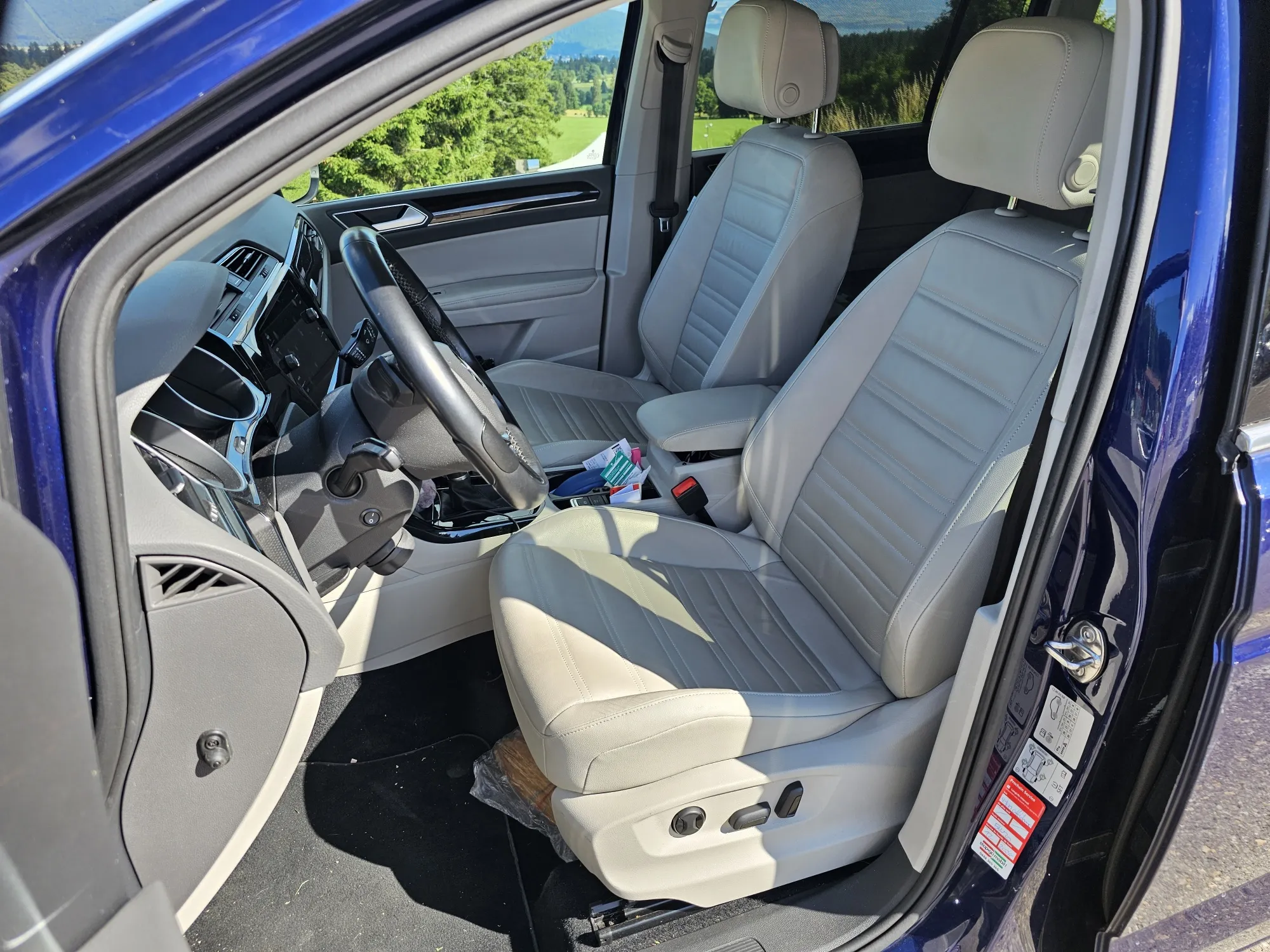 Innenraum eines blauen Autos mit beigen Ledersitzen und modernem Armaturenbrett.