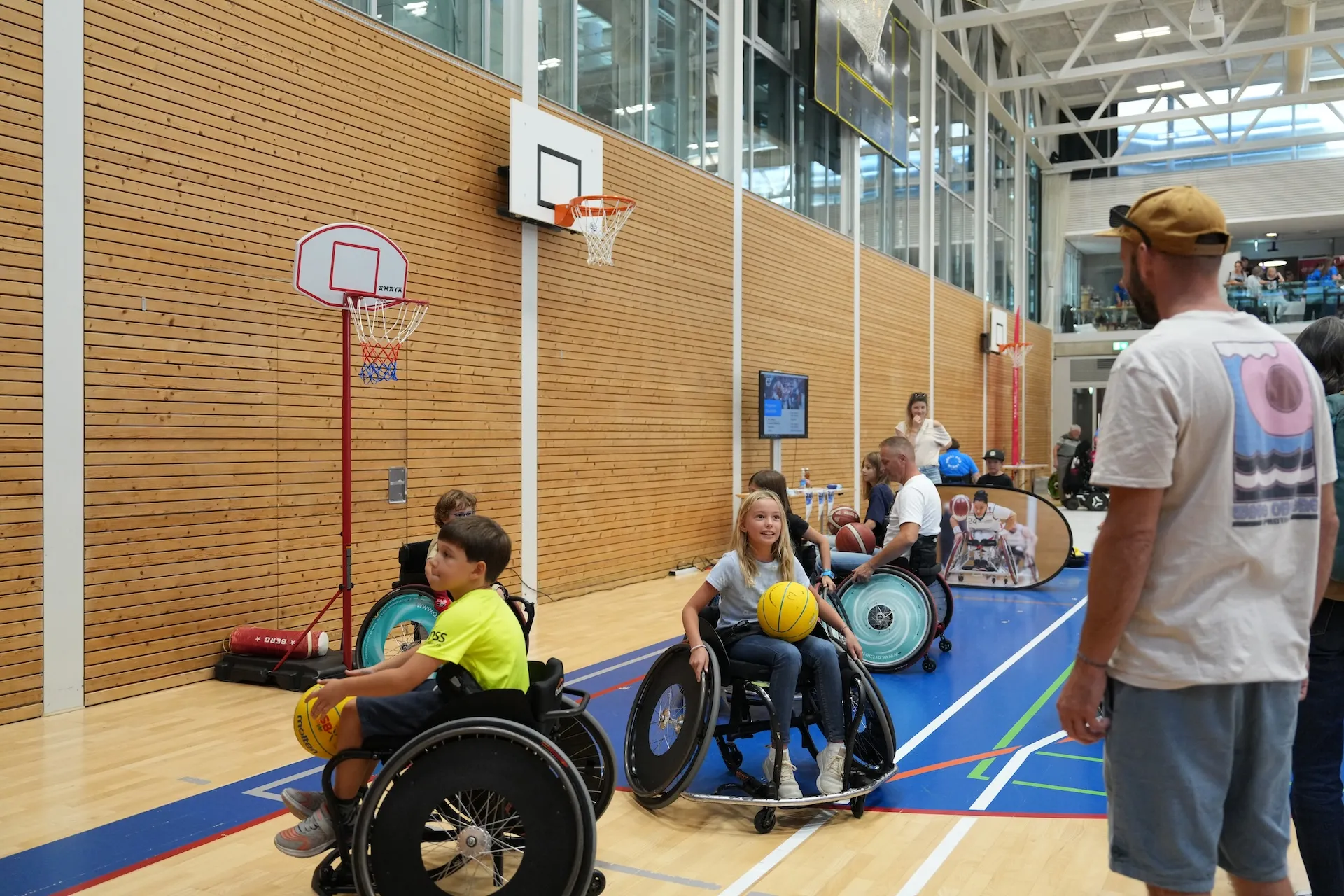 Kinder spielen an den Tagen der offenen Tür der Schweizer Paraplegiker-Gruppe in der Sporthalle Tennis im Rollstuhl.