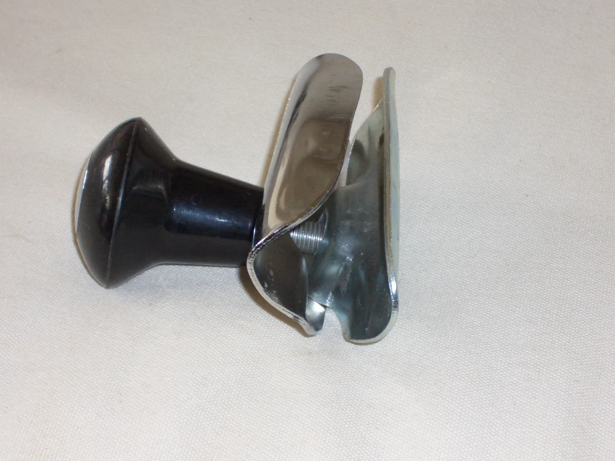 Metal coffee tamper with black plastic handle on light background