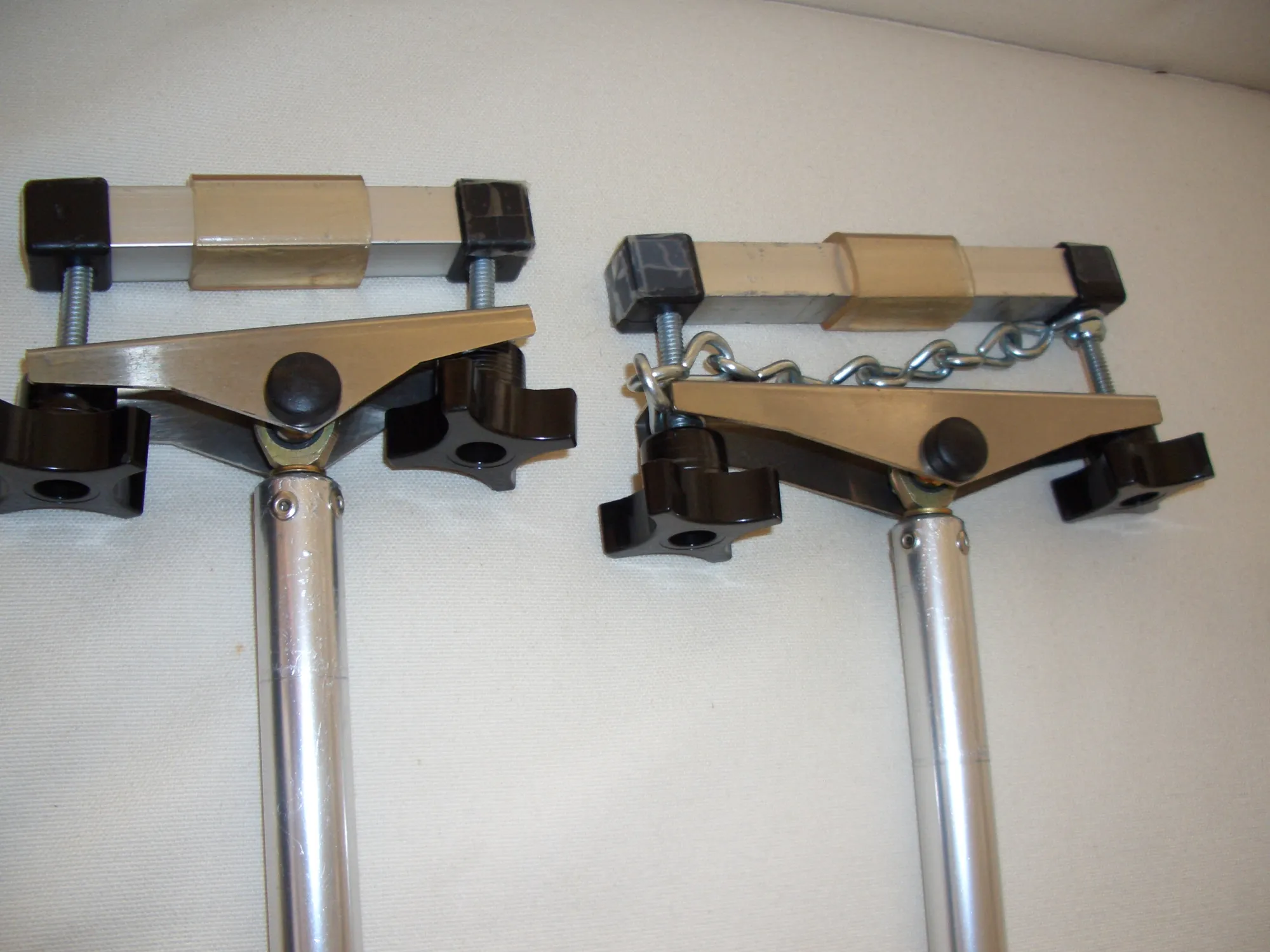 Two wooden bar clamps with metal handles side by side on a textured wall
