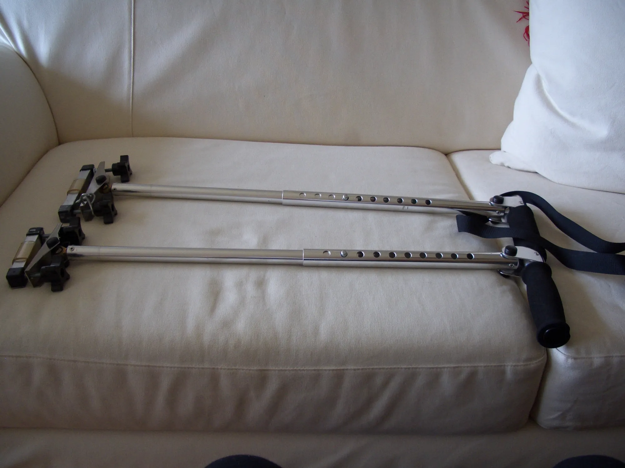Pair of ski poles with black handles and straps on a white couch