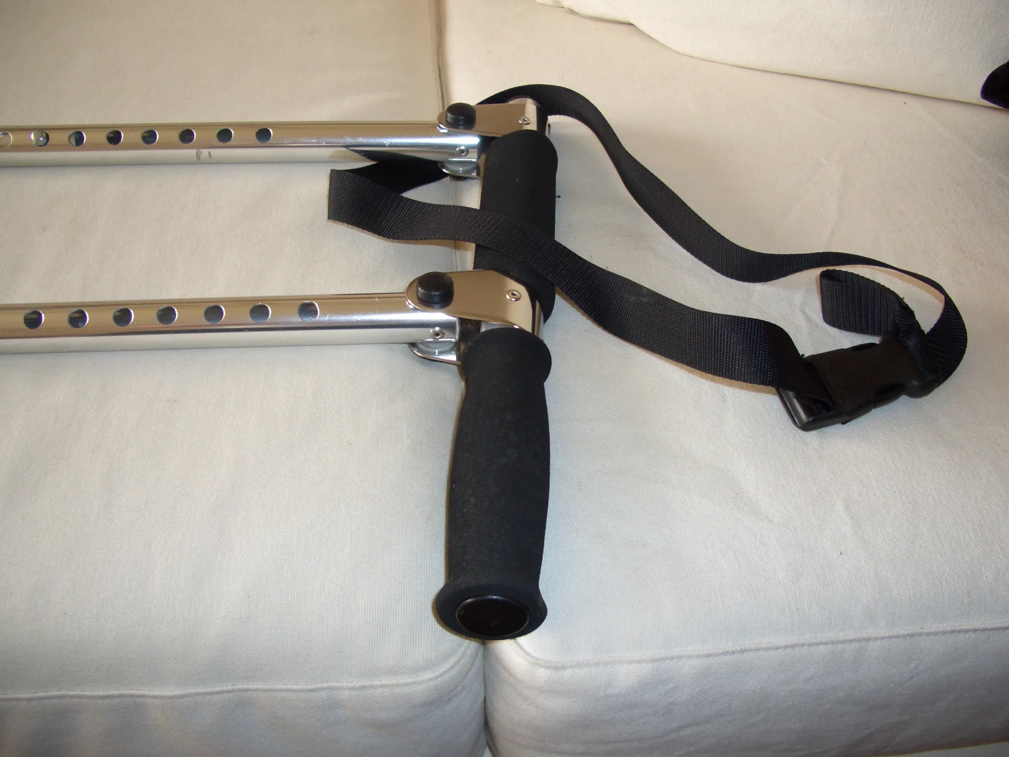 Black nunchaku with wooden handles and a connecting chain on a beige fabric surface.