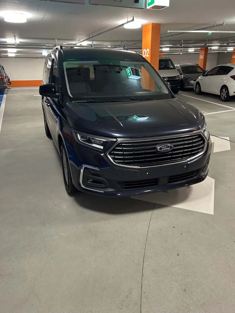 occasion-ford-tourneo-connect-blau-orthotec-03.jpg Dunkelblaues SUV in einer Tiefgarage geparkt.
