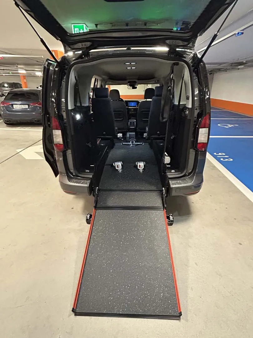 occasion-ford-tourneo-connect-grau-orthotec-09.jpg Behindertengerechter Van mit ausgefahrener Rampe für Rollstuhlzugang im Parkhaus.