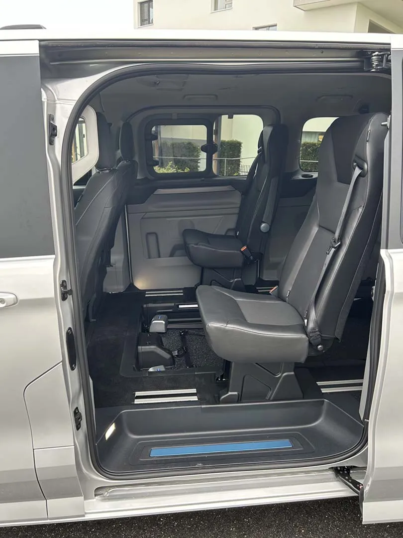 occasion-ford-tourneo-connect-silber-orthotec-04.jpg Innenansicht eines Minivans mit schwarzen Ledersitzen und geöffneter Schiebetür.