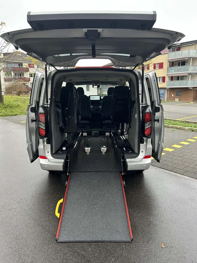 occasion-ford-tourneo-connect-silber-orthotec-06.jpg Rollstuhltransporter mit geöffneter Heckklappe und ausgefahrener Rampe.