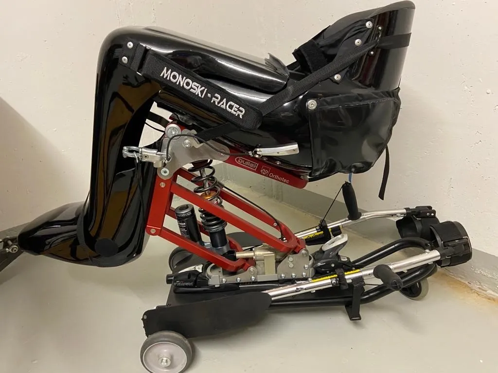 occasion-praschberger-monoskibob-sonderer-02.jpg Zusammengeklapptes rotes Fahrrad mit schwarzer Abdeckung, bereit zum Transport.
