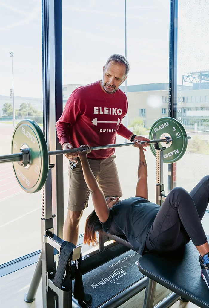 Alexandra Helbling mit einer Hantel, wird von ihrem Trainer unterstützt.
