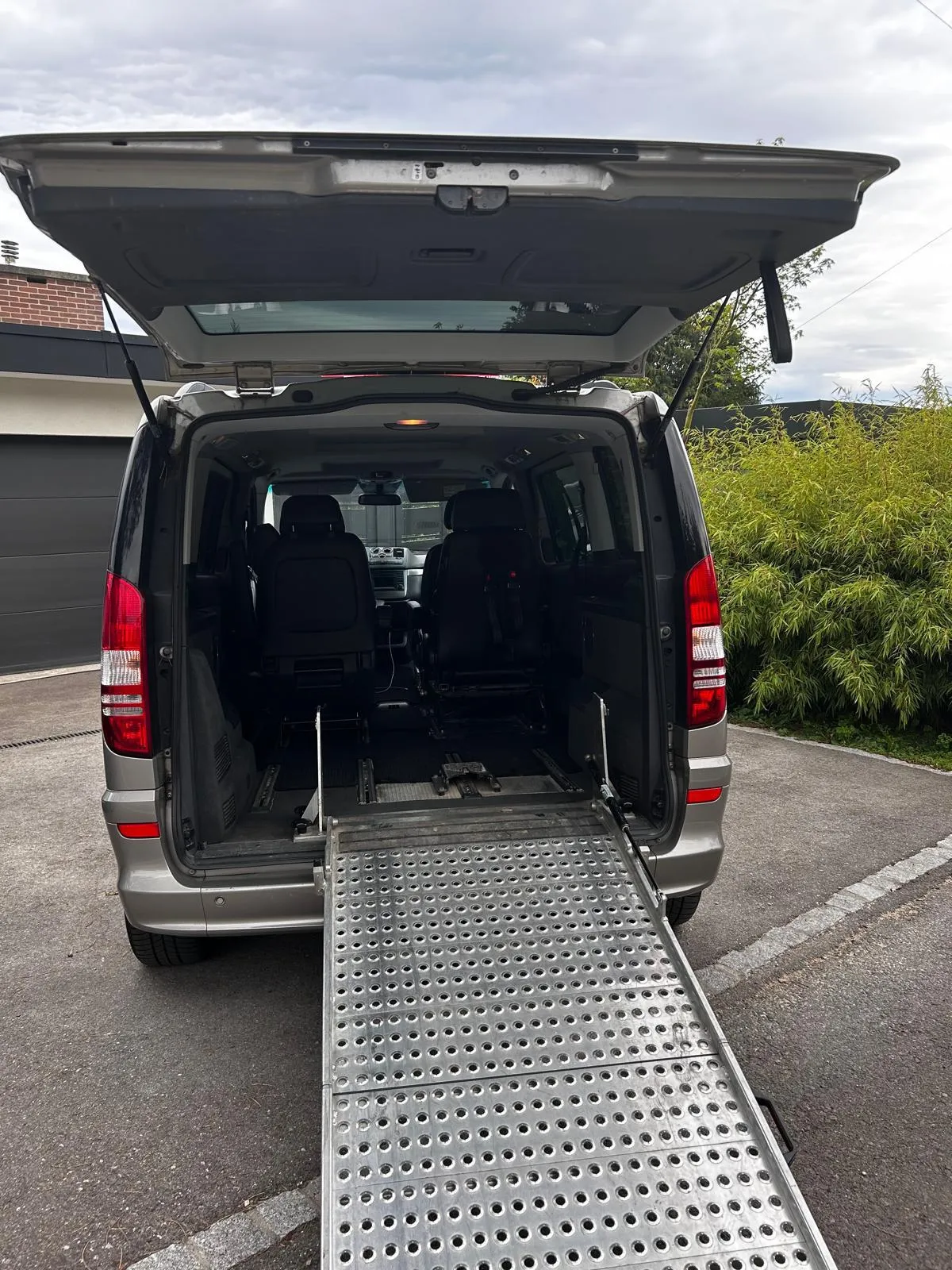 Rollstuhlgerechter Van mit geöffneter Heckklappe und ausgefahrener Rampe.