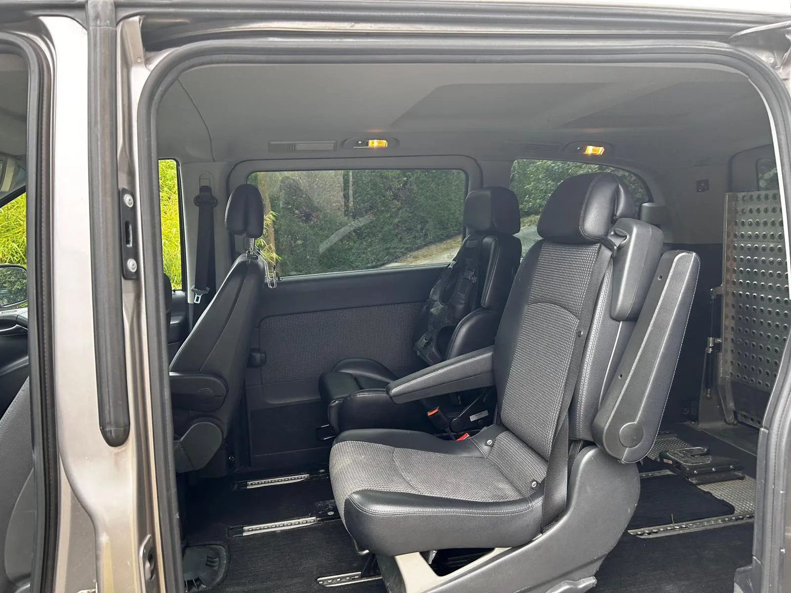 Innenraum eines Minivans mit schwarzen Ledersitzen und geöffneter Schiebetür.