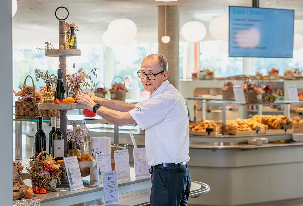 Ilidio Manuel Silva Mahado platziert einen Deko-Kürbis im Centro und lächelt dabei über seine Schulter in die Kamera.