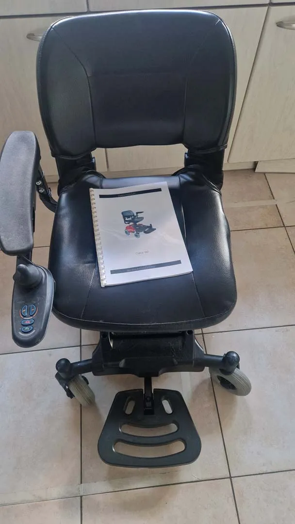Schwarzer Bürostuhl mit Armlehnen und Fußstütze, ein weißes Papier liegt auf dem Sitz.