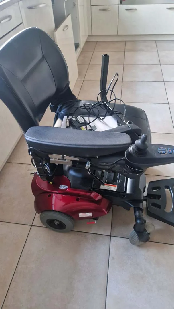 Elektrischer Rollstuhl mit Katze, die auf dem Sitz schläft.
