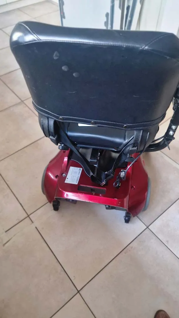 Roter Elektromobilitätsroller mit Sitz und Einkaufskorb auf Fliesen.