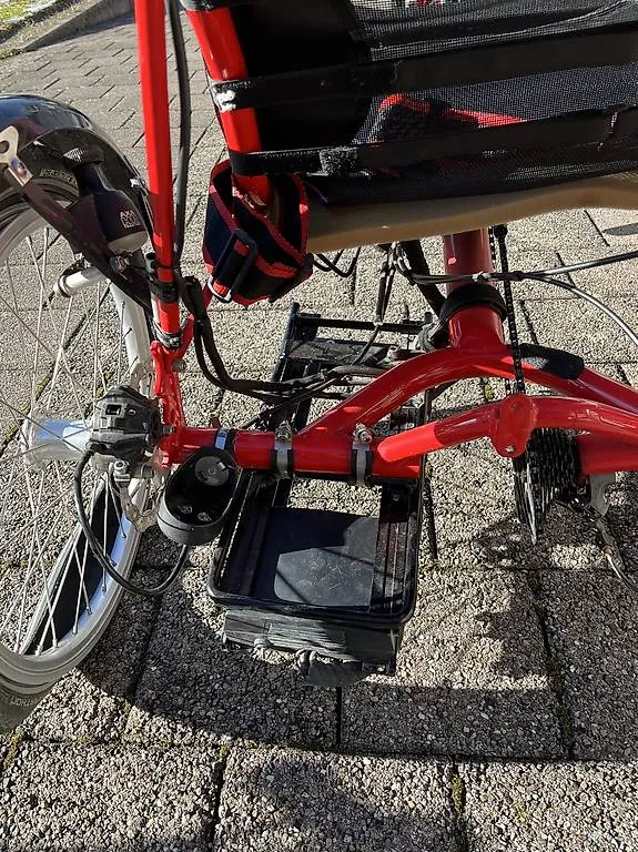 occasion-hasebike-ammann-01.jpg Rotes Fahrrad mit Klappständer auf Pflasterstein-Oberfläche geparkt.