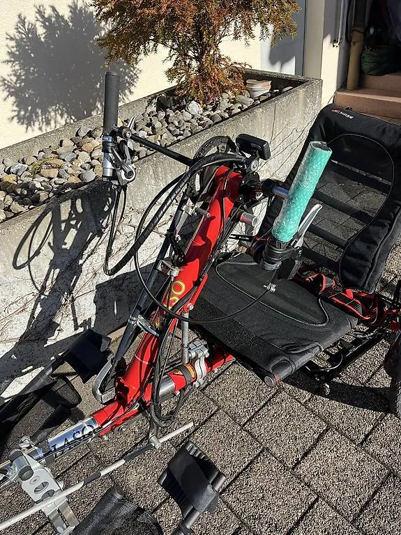 occasion-hasebike-ammann-05.jpg Rotes E-Bike und Elektroroller auf Bürgersteig vor Fahrradständern geparkt.