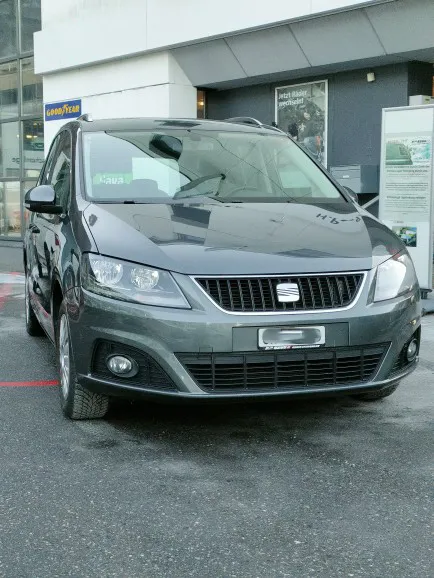Grauer SEAT-Kombi parkt vor einem Gebäude mit Glasfassade.