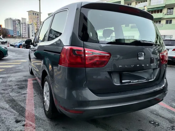 Grauer Seat-Familienvan geparkt auf einer Straße in einer Stadt mit Gebäuden im Hintergrund.