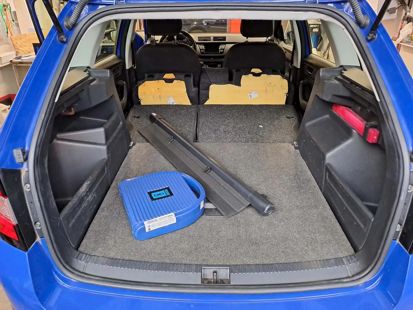 Geräumiger Kofferraum eines blauen Autos mit offenem Kofferraumdeckel und umgeklappten Rücksitzen.