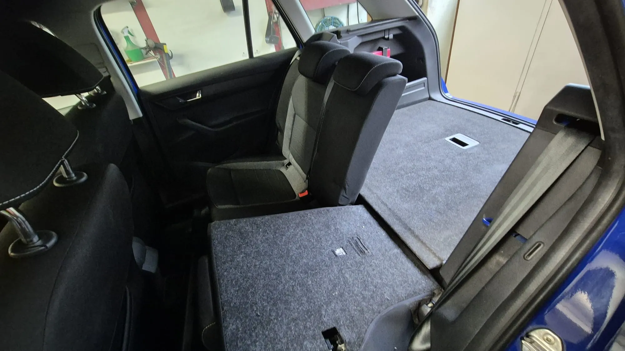 Rücksitz eines Autos mit aufgeklappten Sitzflächen, die einen flachen Laderaum bilden.