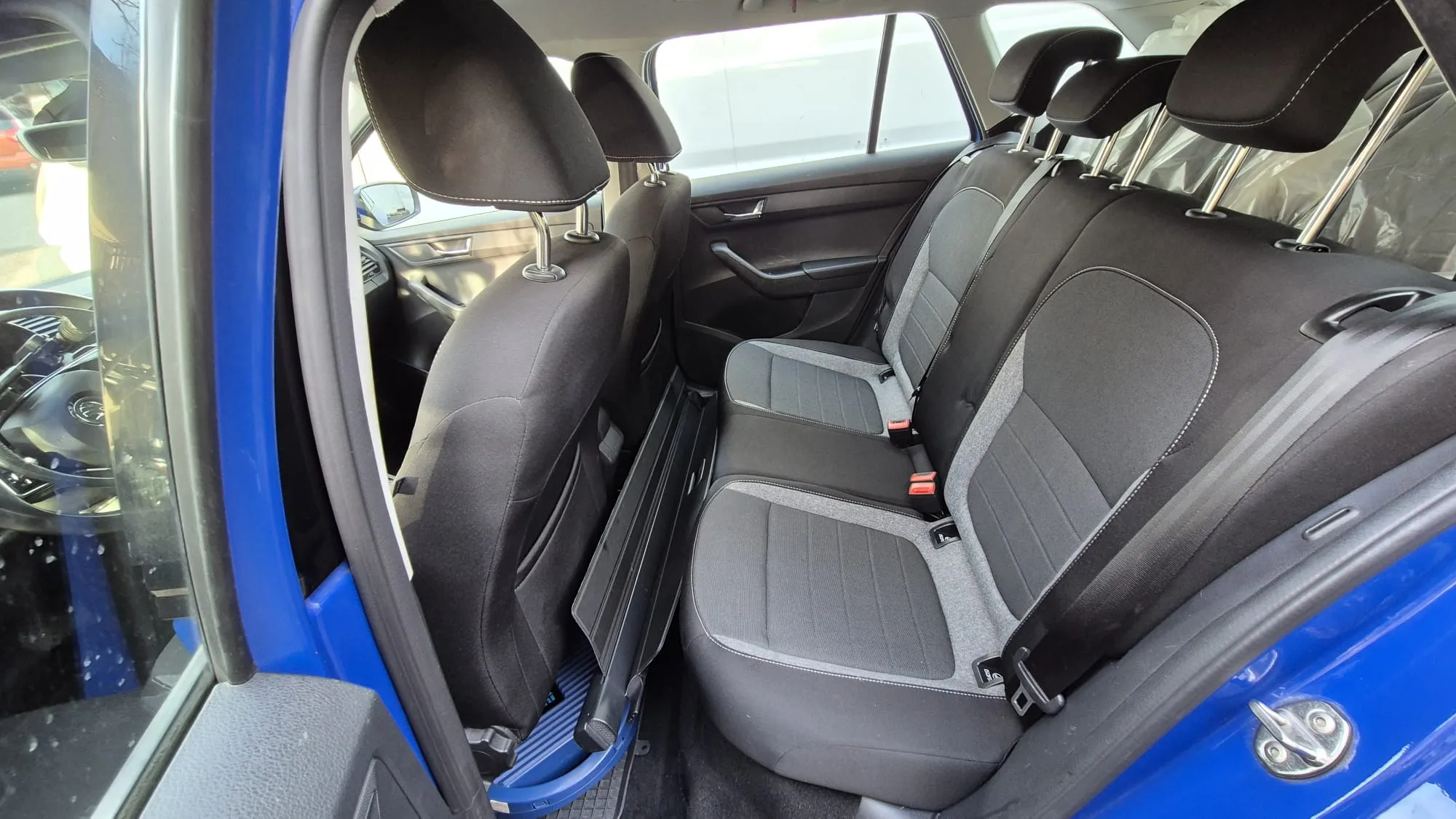 Rücksitze eines blauen Autos mit grauen Stoffbezügen und schwarzen Kopfstützen.