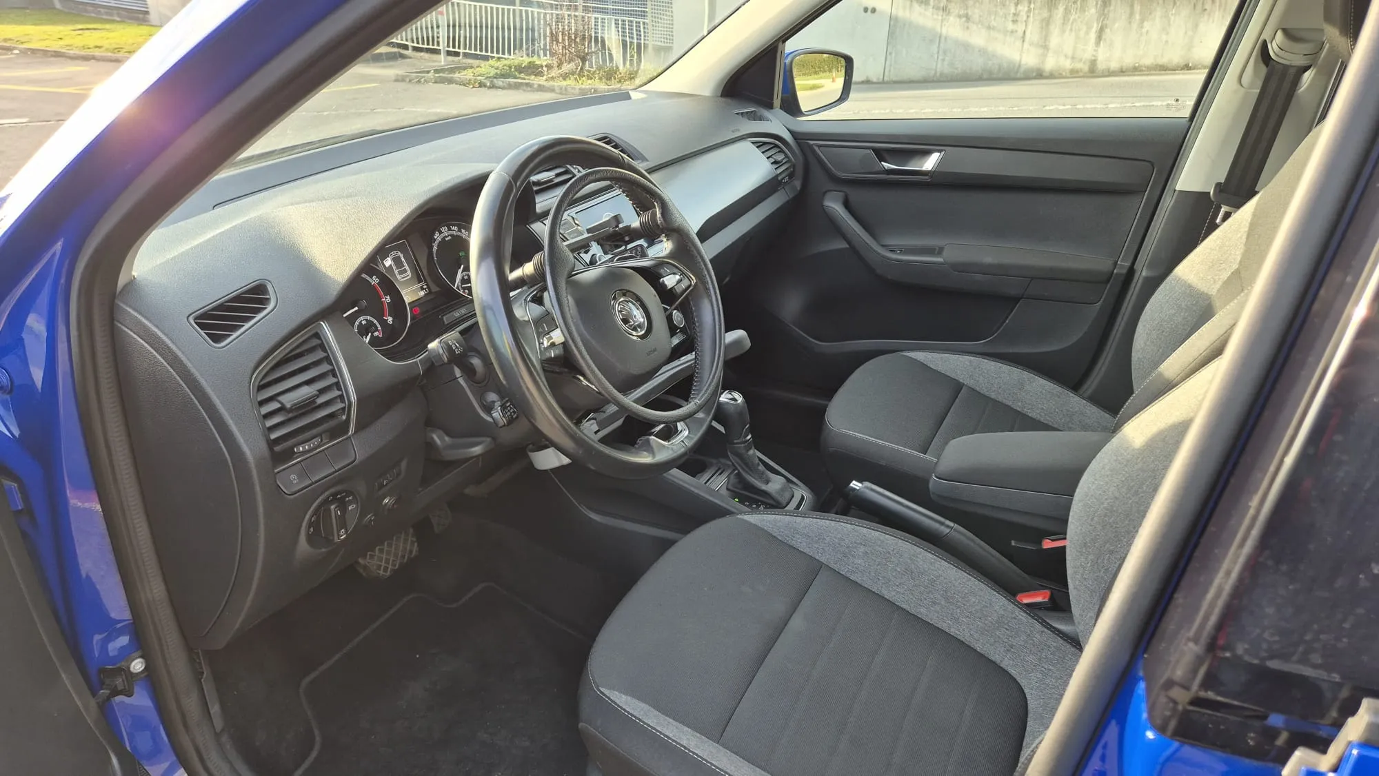 Innenansicht eines blauen Autos mit schwarzem Interieur und Lenkrad.