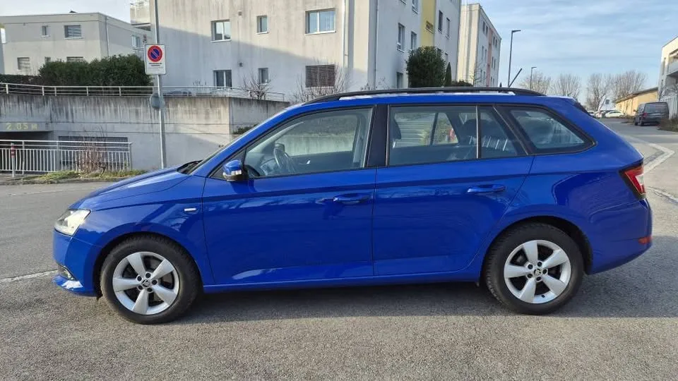 Blauer Kombi-Sportwagen parkt vor Gebäuden an einer Straße.