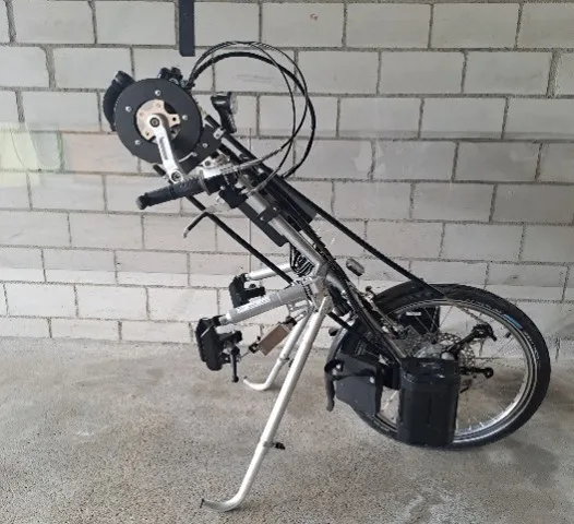 occasion-stricker-elektro-vorspannbike-kaelin-02.jpg Zusammengeklappter Golfwagen mit Rädern, vor einer weißen Mauer stehend.