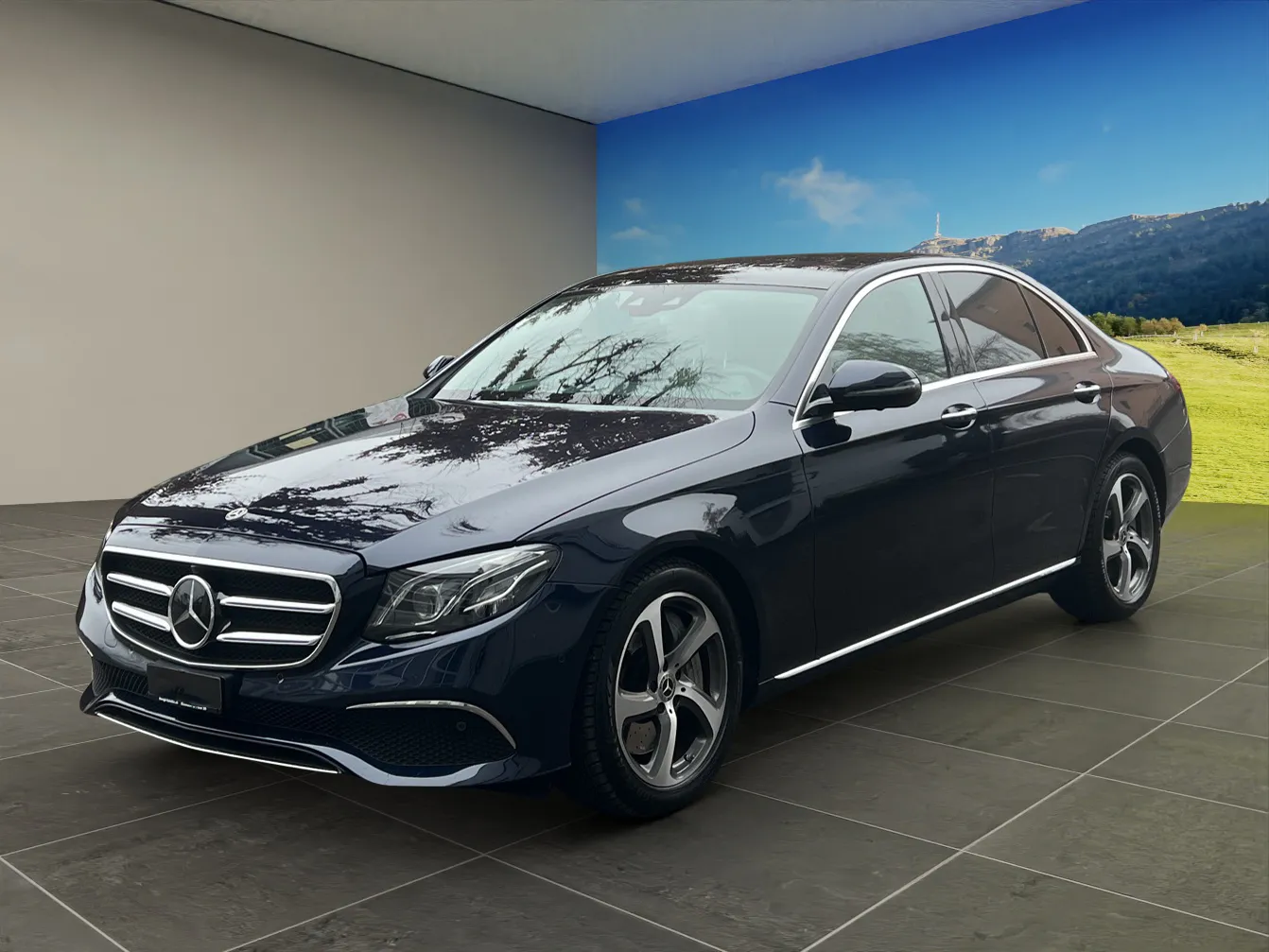Schwarzer Mercedes-Benz E-Klasse vor Gebäude mit blauem Himmel und Bergen im Hintergrund.