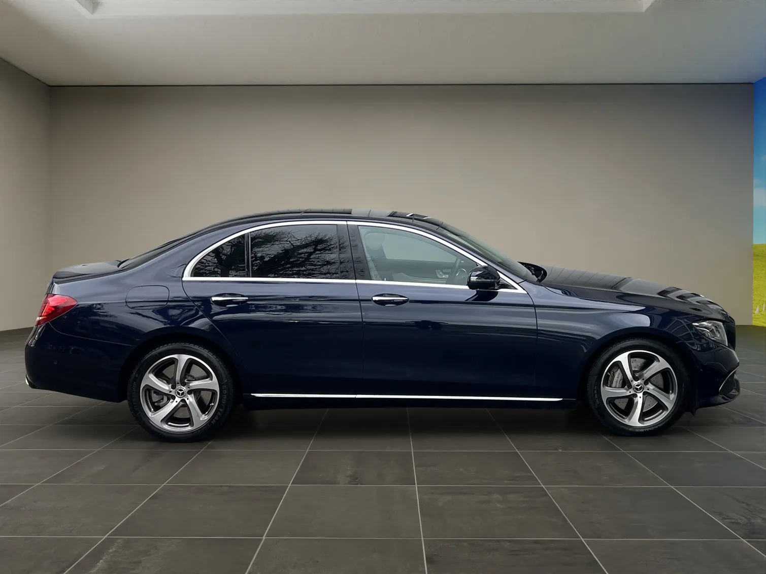 Dunkelblaue Luxuslimousine in einem Autohaus-Showroom mit glänzendem Boden.