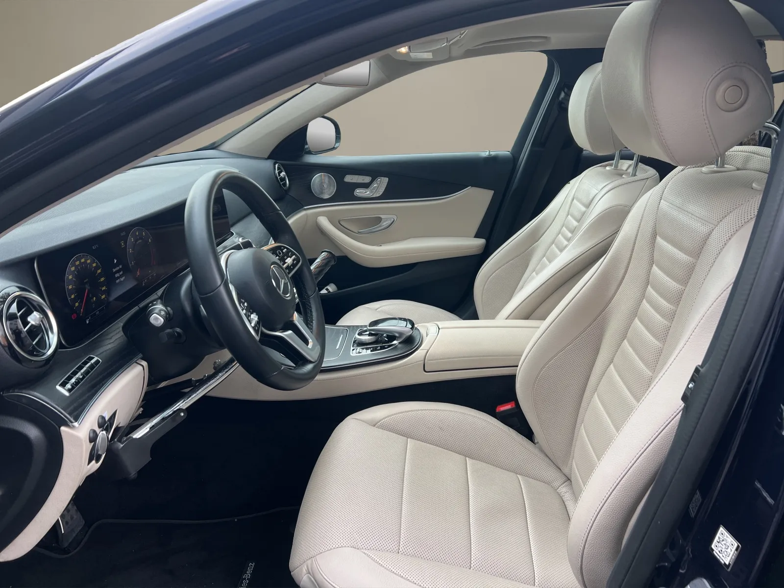 Elegantes Interieur eines Luxusautos mit cremefarbenen Ledersitzen und hochwertigem Armaturenbrett.