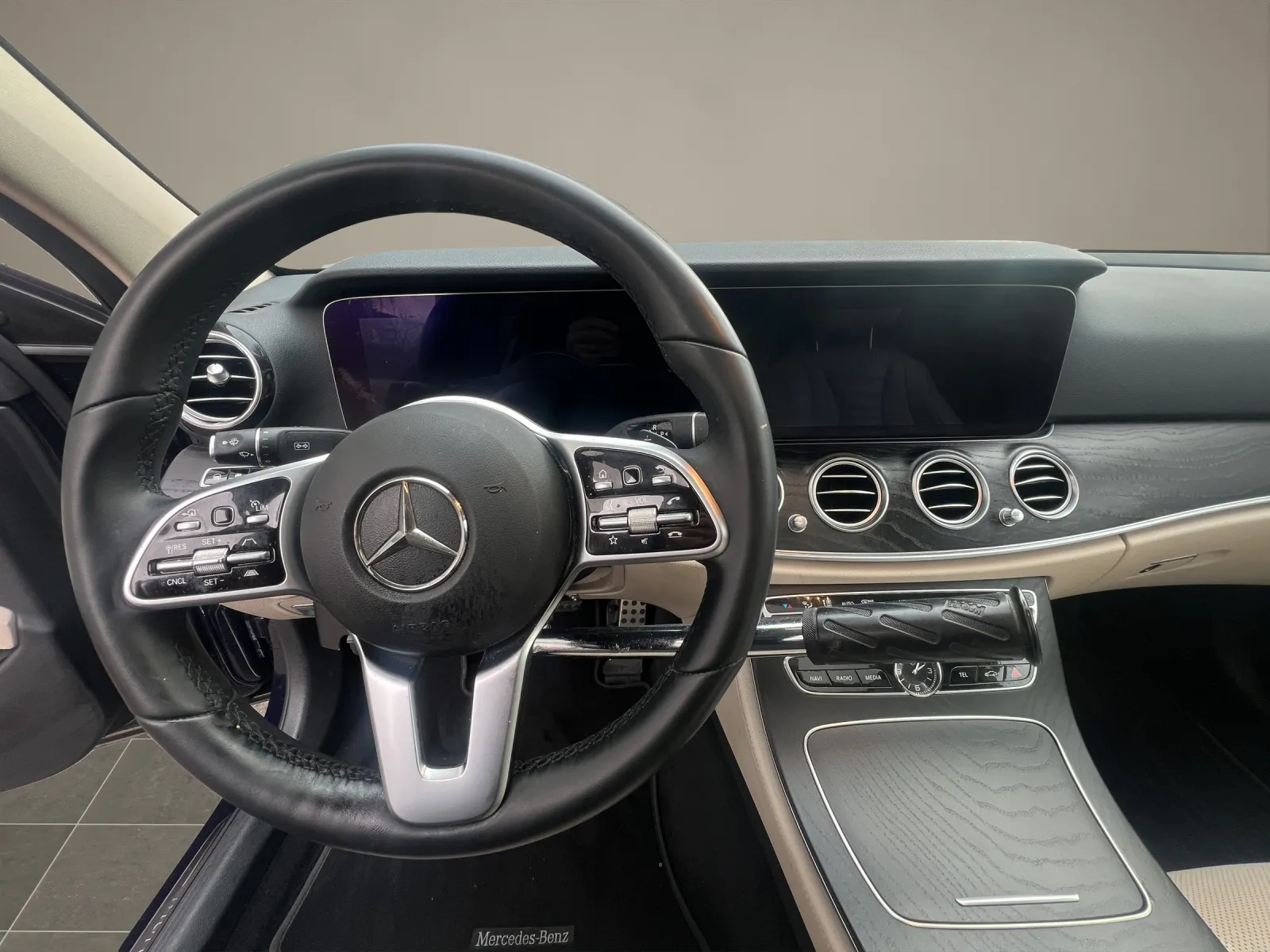 Lenkrad und Armaturenbrett eines Mercedes-Benz mit digitalem Display und Mittelkonsole.