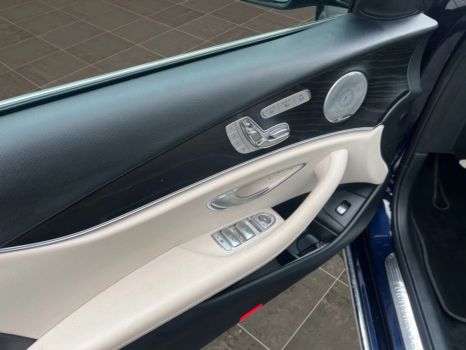 Nahaufnahme der Türinnenverkleidung eines Luxusautos mit Lederpolsterung und Metallakzenten.
