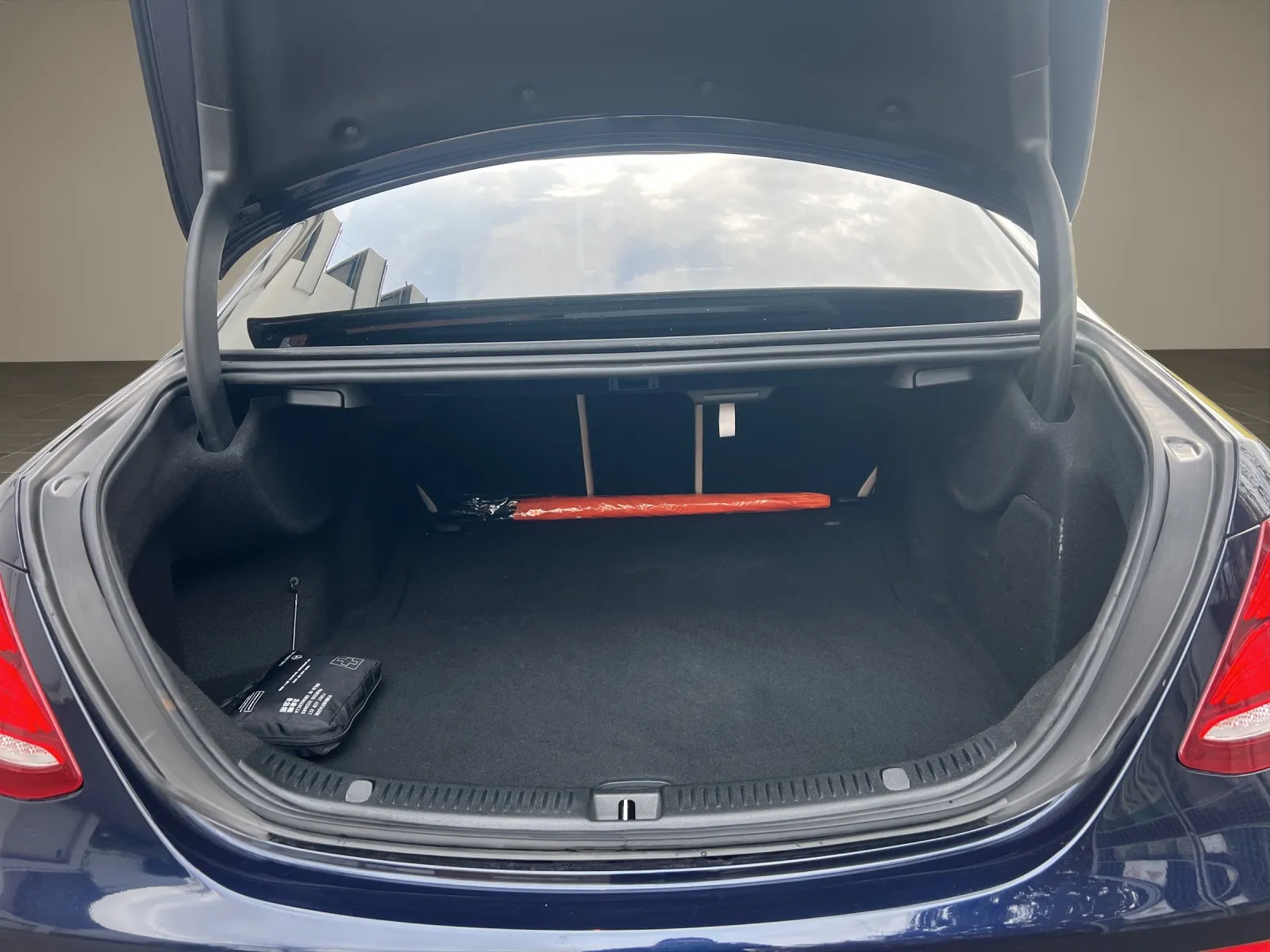Offener Kofferraum eines dunkelblauen Autos mit leerem Innenraum und roter Sicherheitsleuchte.