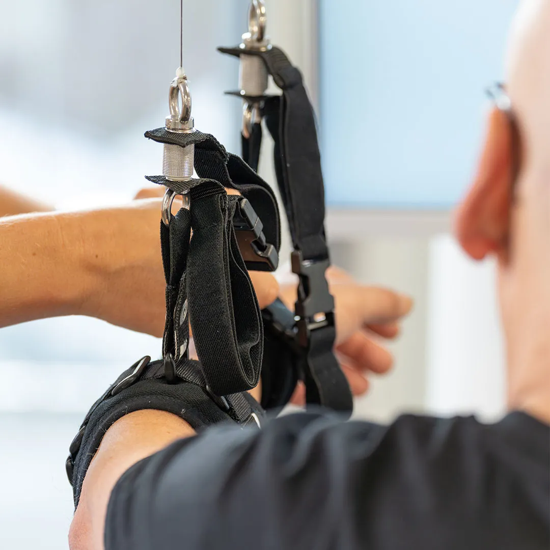 Ein Arm des Patienten ist an einem Therapieroboter mit einer Schlaufe befestigt