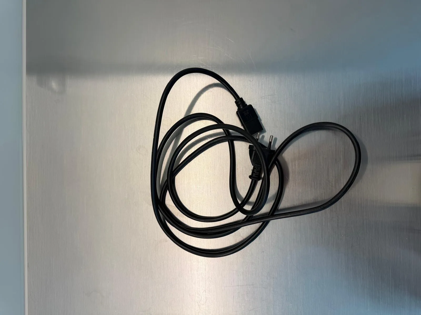 occasion-cough-assist-ofner-01.jpg Schwarzes Ladekabel auf grauem Hintergrund, spiralförmig angeordnet.
