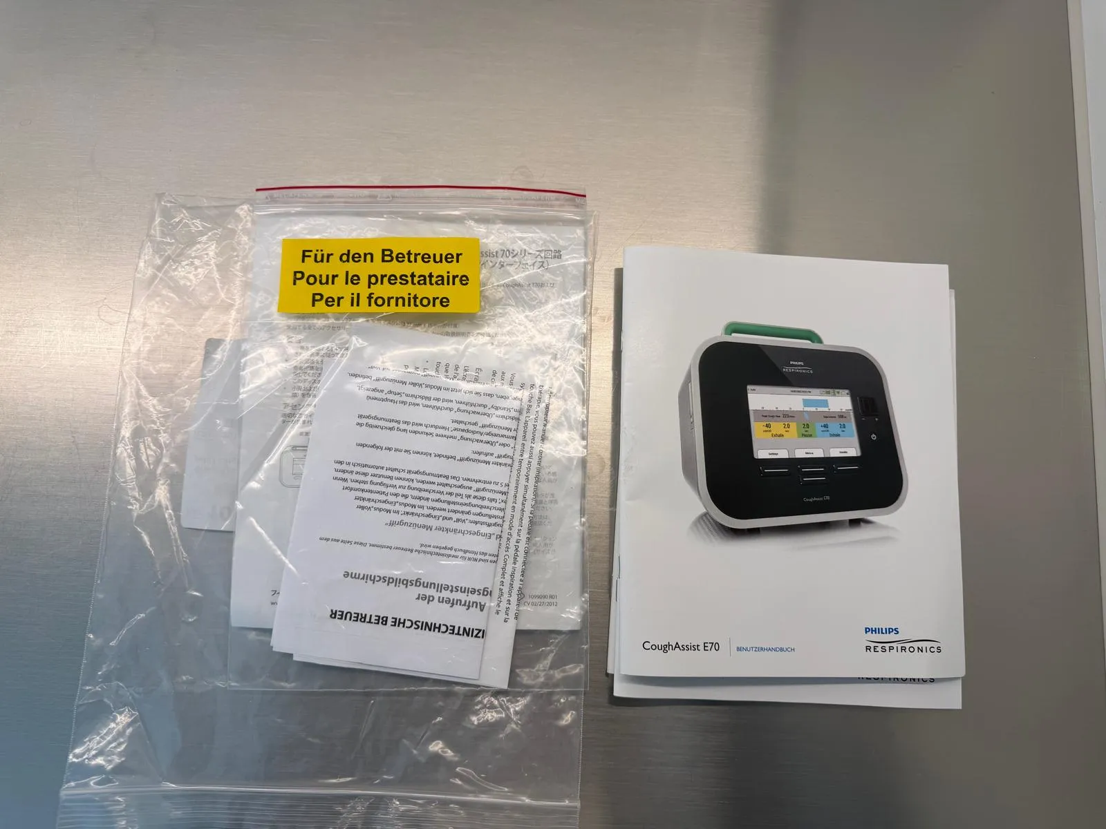 occasion-cough-assist-ofner-07.jpg Thermostat mit Benutzerhandbuch und Warnhinweisen auf einem Tisch.