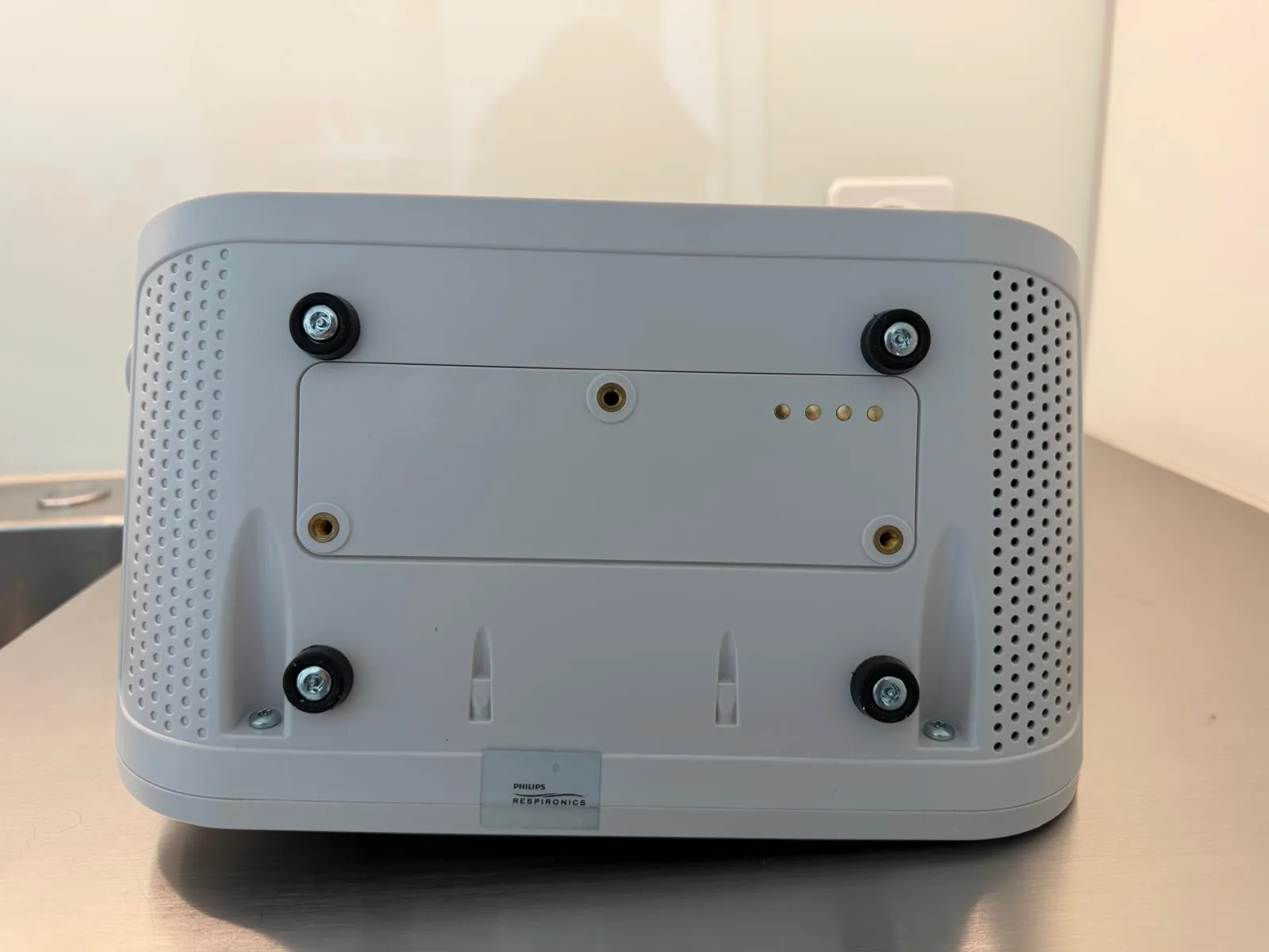 occasion-cough-assist-ofner-08.jpg Grauer Netzwerk-Router mit runden Lüftungsöffnungen und schwarzen Gummifüßen.