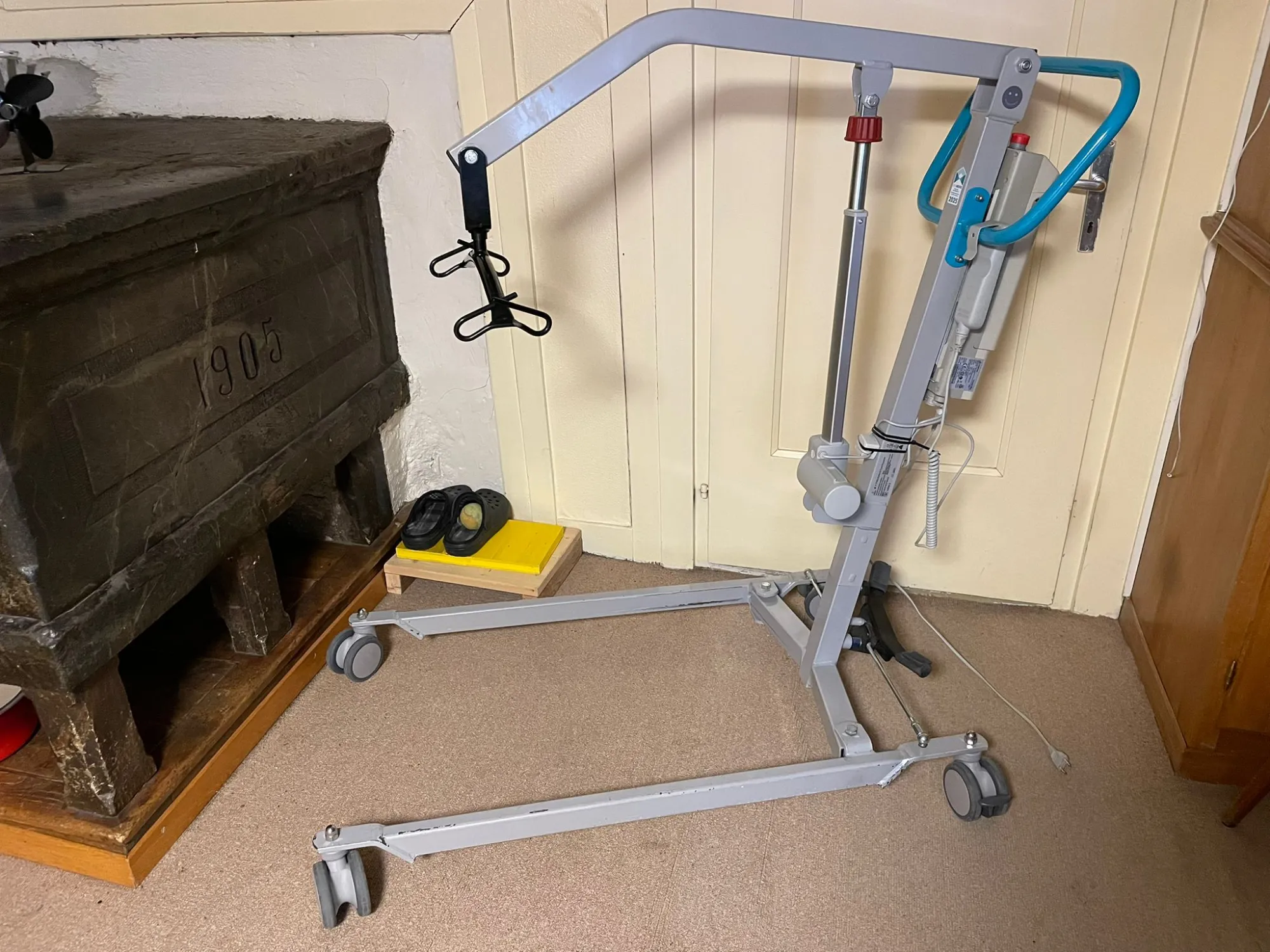 occasion-pateintenlifter-krumenacher-02.jpg Patientenlifter neben einem Krankenhausbett mit gelbem Fußpedal und blauem Griff.