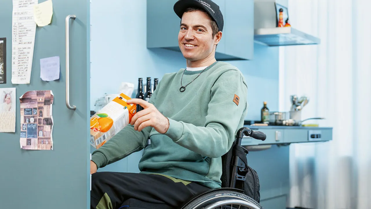 Mann im Rollstuhl am Kühlschrank