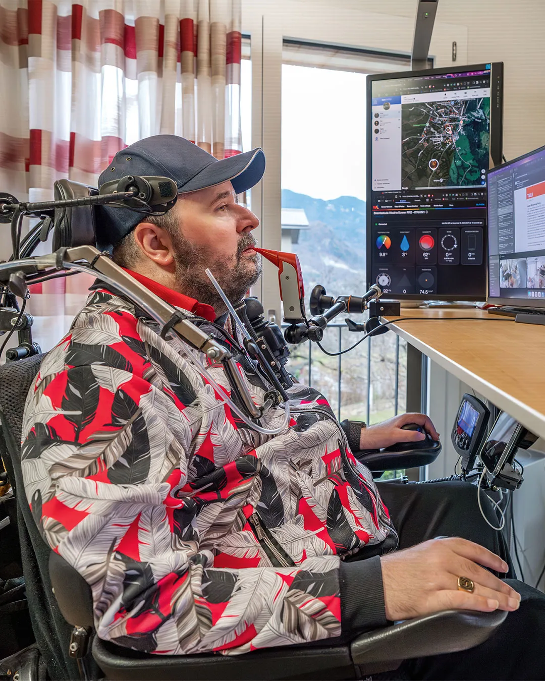 Gion Stiffler sitzt an seinem Schreibtisch und steuert seinen Computer mit dem Mund.