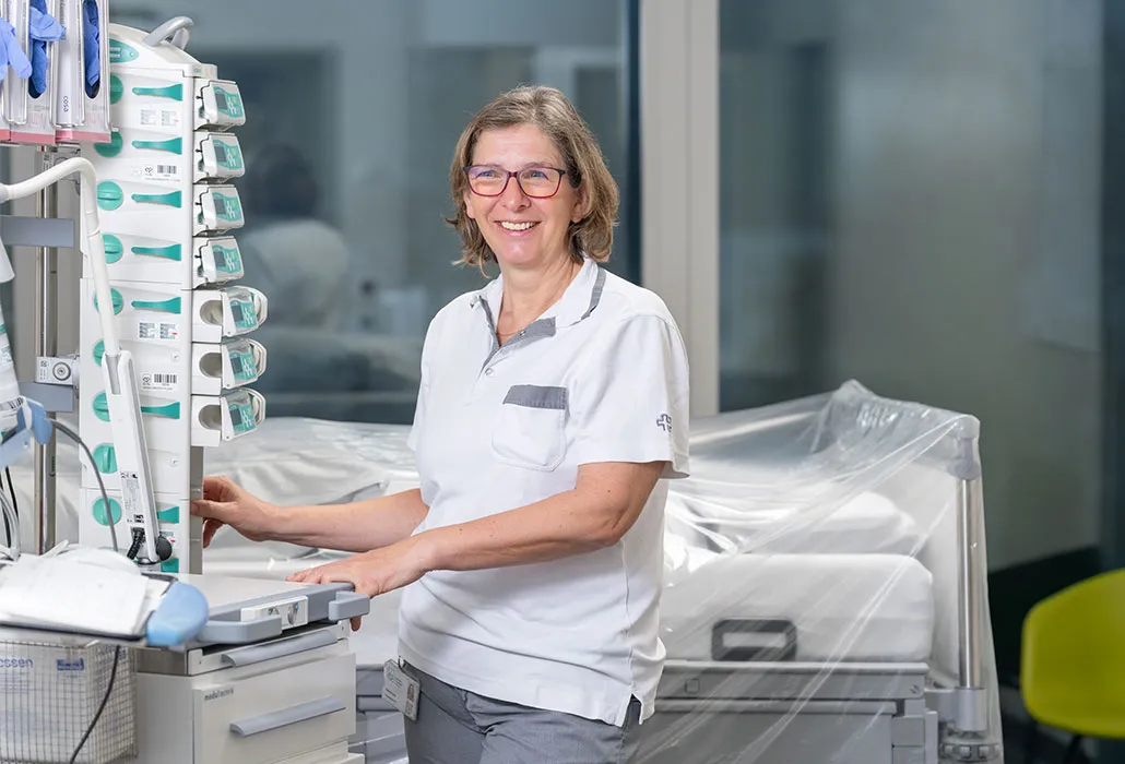 Isolde Kunde steht in einem Zimmer auf der Intensivstation und stellt die Geräte, die neben dem Bett stehen, ein.
