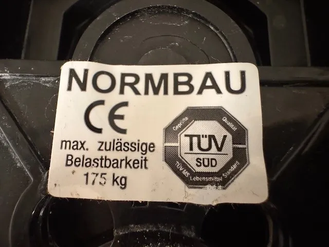 occasion-normbau-duschsitz-lippuner-03.jpg Nahaufnahme eines Normbau-Etiketts mit CE-Kennzeichnung und TÜV-Logo.