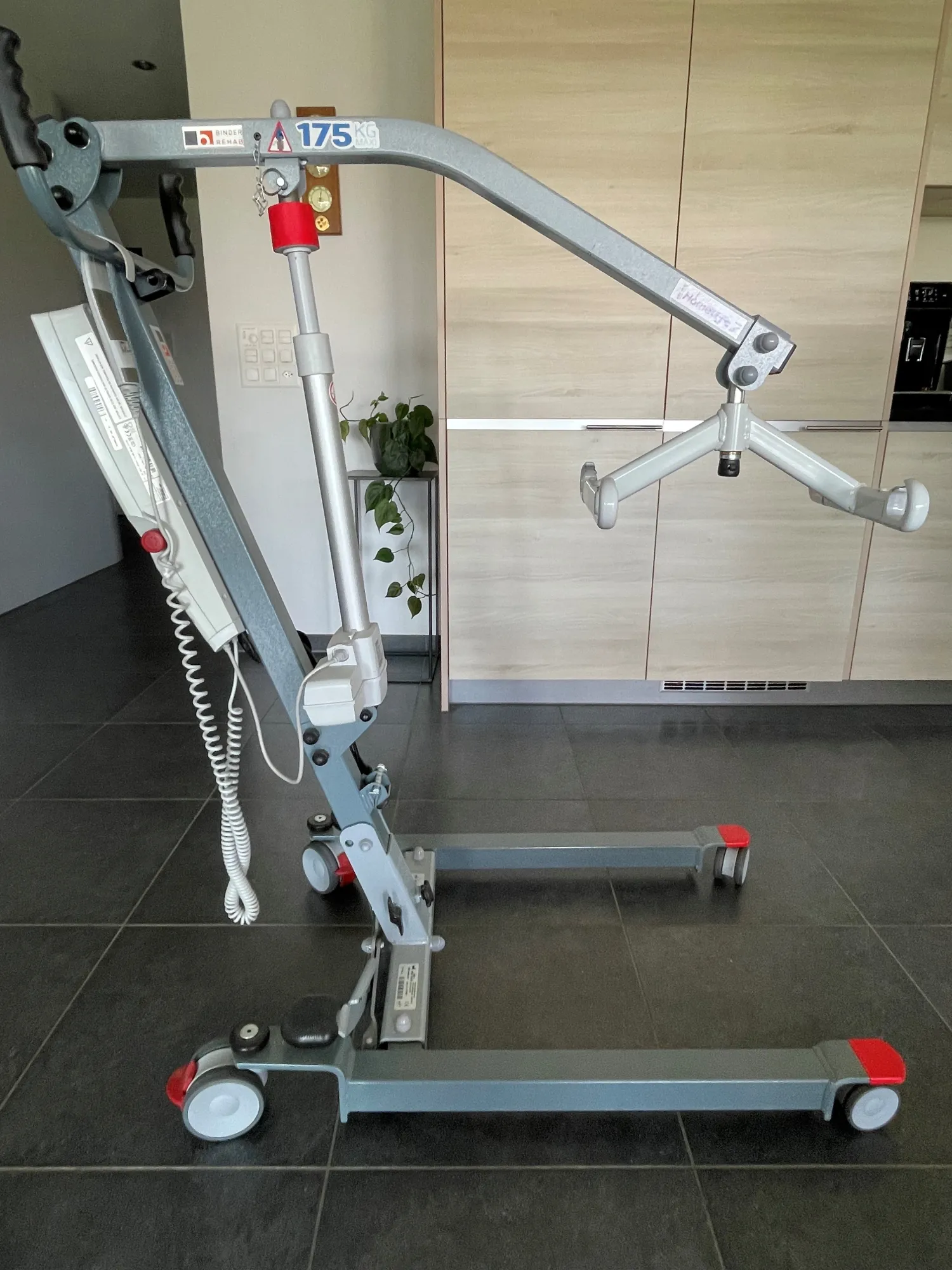 occasion-patientenheber-horne-maurer-01.jpg Mobiler Patientenlifter mit verstellbarem Ausleger und Griff in einem Krankenhauszimmer.