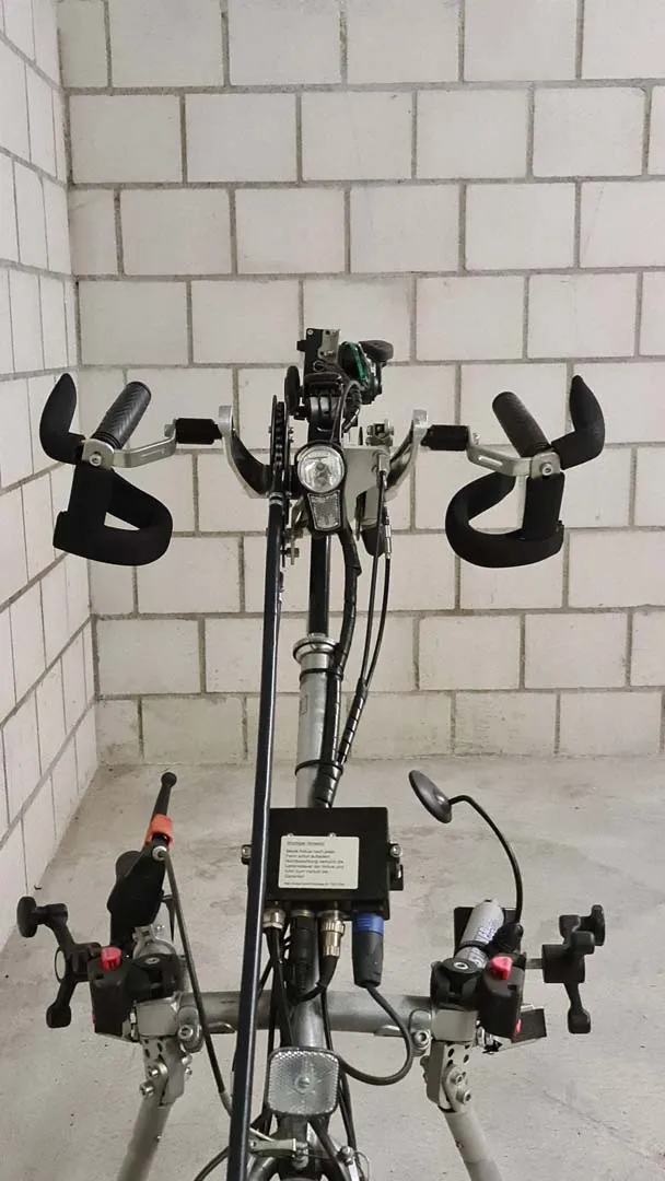 occasion-stricker-vorspannbike-nguyen-05.jpg Schwarze Graffiti-Figur mit ausgestreckten Armen an weißer Fliesenwand, davor Stativ mit Kameras.