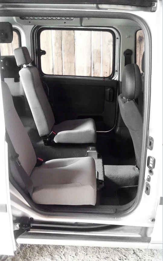 Rücksitz eines Kleintransporters mit grauen Sitzen und offenem Seitenfenster.